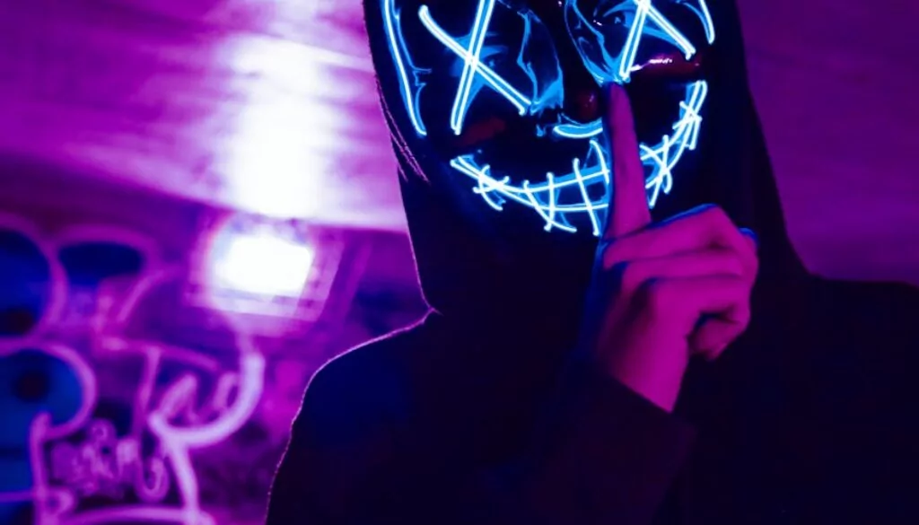 person wearing led mask doing silence gesture