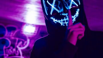 person wearing led mask doing silence gesture