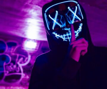 person wearing led mask doing silence gesture