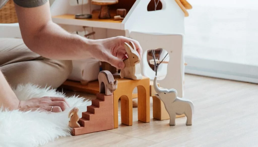 anonymous crop parent playing with toys on floor at home