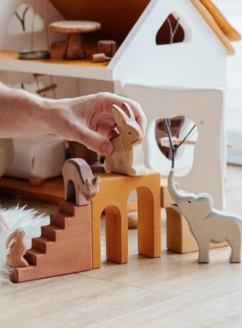 anonymous crop parent playing with toys on floor at home