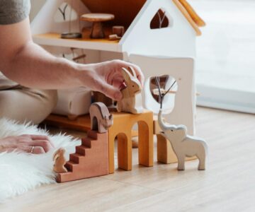 anonymous crop parent playing with toys on floor at home